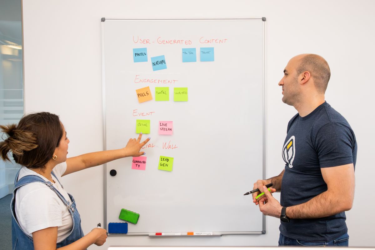 Two colleagues planning a software project with sticky notes on a whiteboard, the scoping work behind building your own travel website