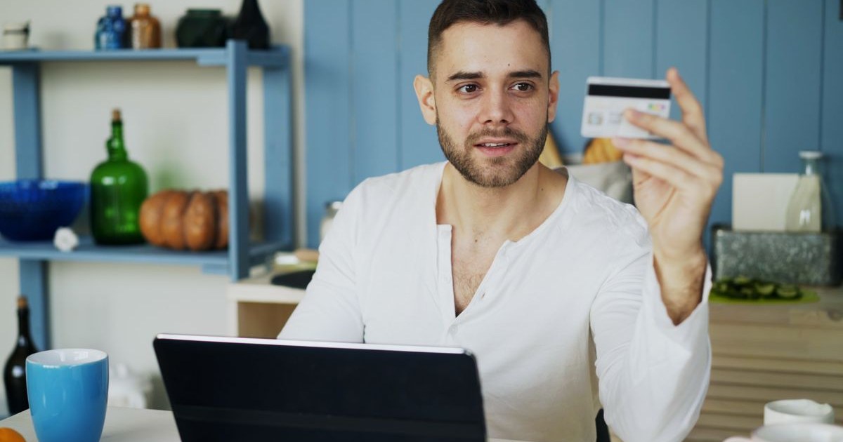 Customer paying for an online booking with a credit card and laptop, the final sell price a travel markup strategy decides