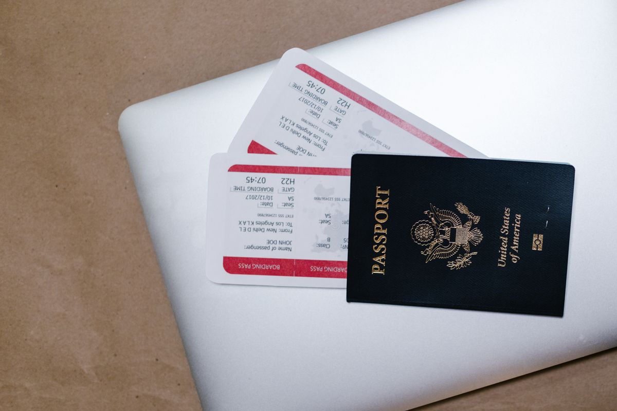 Passport and printed flight boarding passes resting on a laptop, representing booking travel online