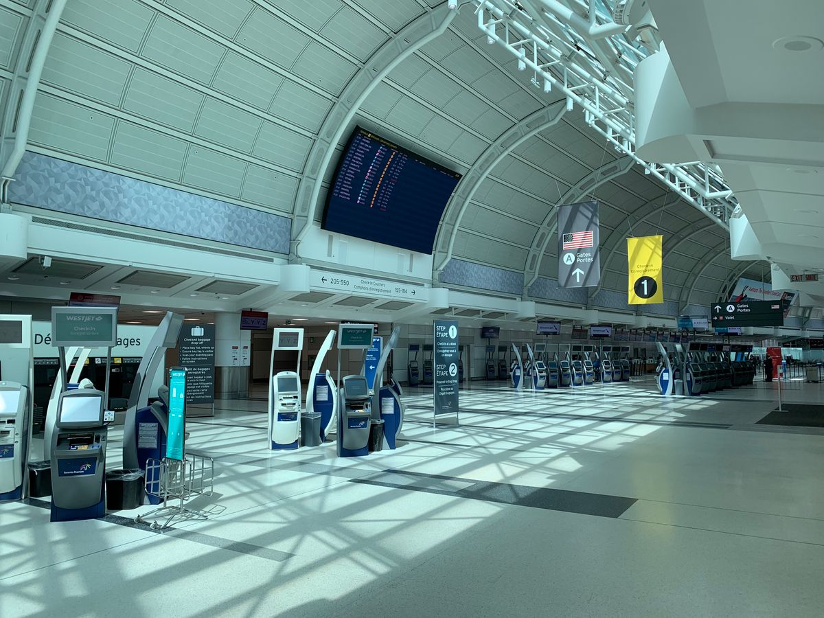 Airport hall with a departures board and self check-in kiosks, representing the live flight content a travel website must connect to through GDS and supplier APIs