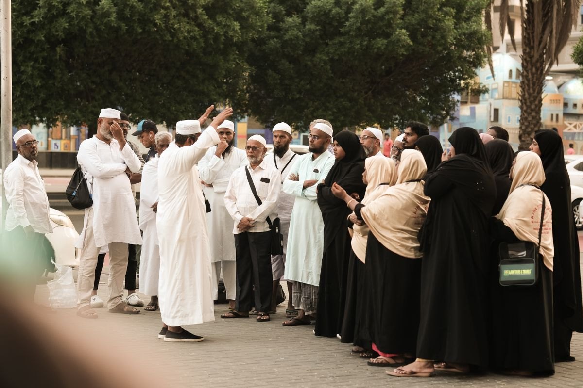 Group of Umrah pilgrims listening to their group leader on a street in Saudi Arabia, the kind of group booking an Umrah website must handle