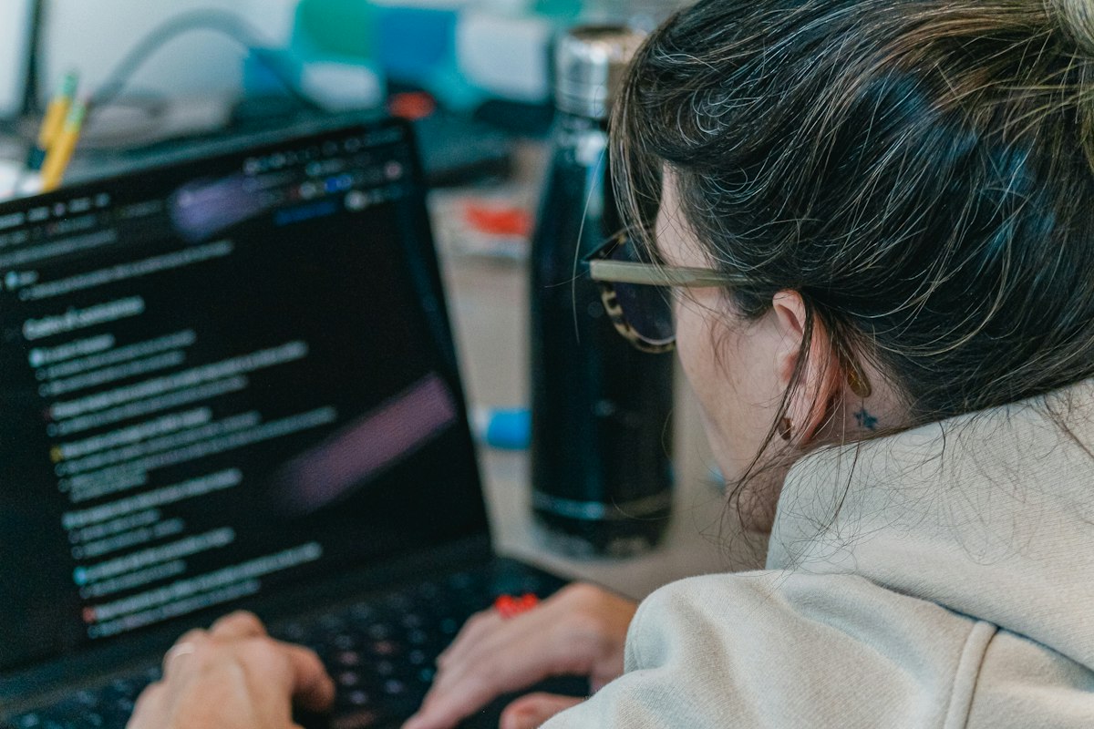Developer writing code on a laptop, the work behind a custom-built travel booking website