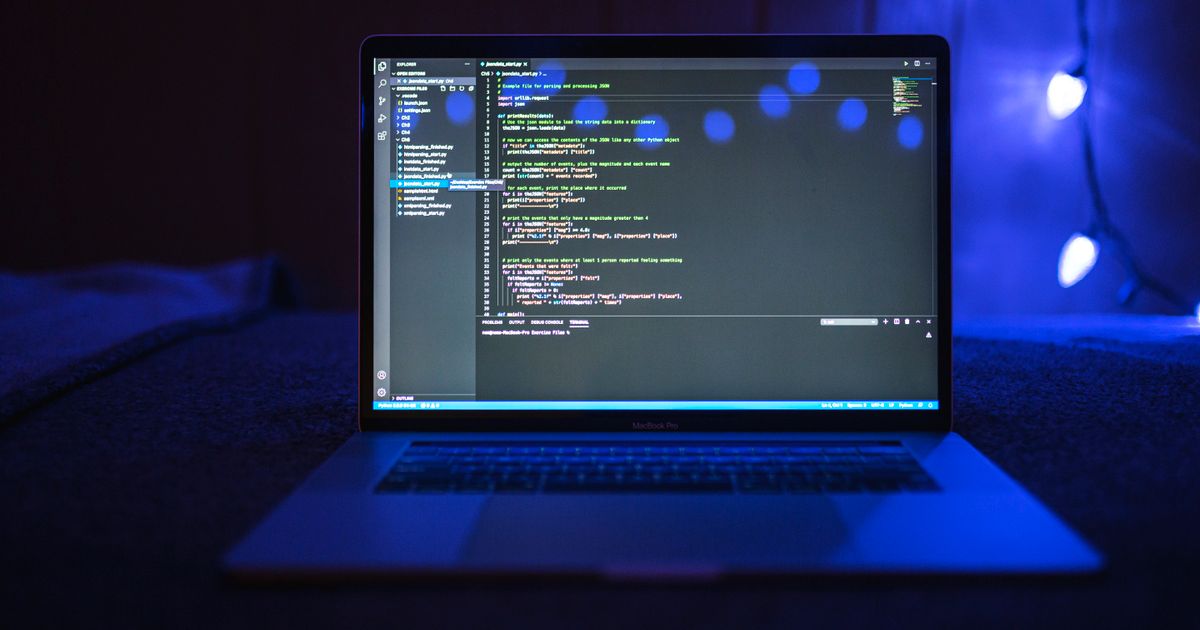 Laptop screen showing code in a dark room, representing the API integration work that connects Amadeus flight content to a travel website