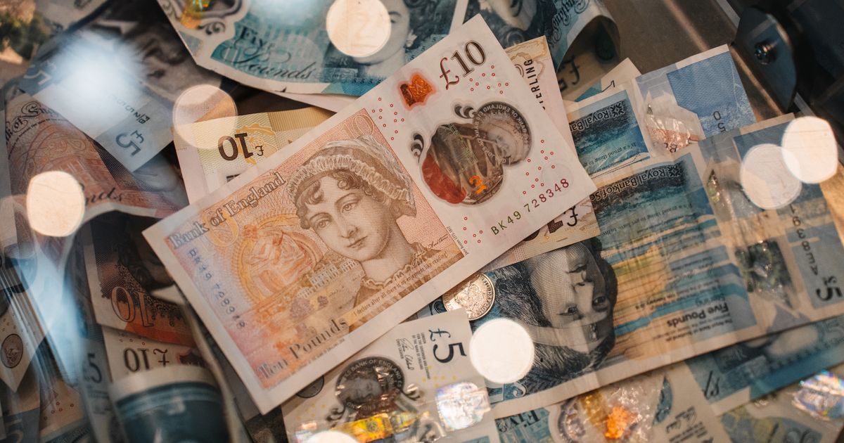 British £5 and £10 banknotes and coins spread on a table, representing the choice between paying a monthly platform fee and giving up booking margin