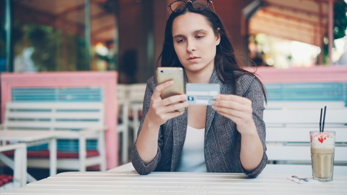 Traveller entering bank card details on a phone to complete an online holiday booking payment