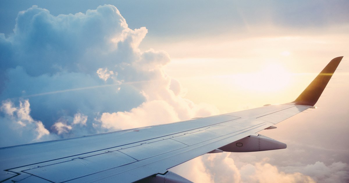 Airplane wing above the clouds, representing ATOL-protected flight-inclusive holidays for UK travellers